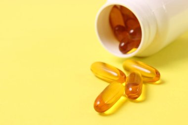 Renkli arka planda Omega-3 kapsülleri. Balık yağı, sağlıklı besinler.