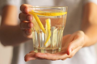 Dişi ellerinde limon olan bir bardak su