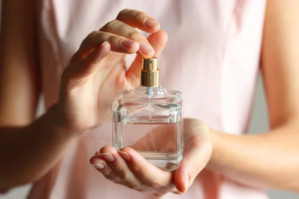 The girl uses perfume. Perfume in female hands.