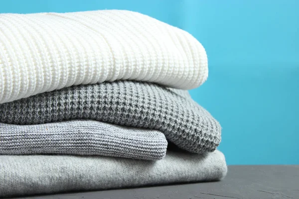 Ahşap bir masada, arka planda sıcak süveter yığını. Sonbahar ve kış giysileri.