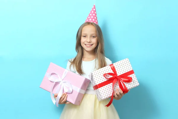 お祝いのキャップに小さな女の子の肖像画と色の背景に彼女の手の中に贈り物 誕生日 プレゼント — ストック写真