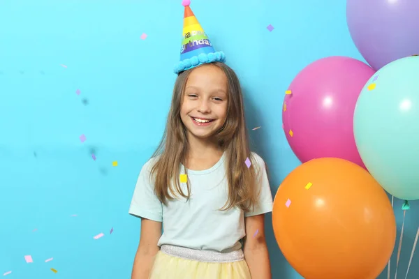 お祝いのキャップと色の背景に風船で小さなかわいい女の子の肖像画 誕生日 — ストック写真