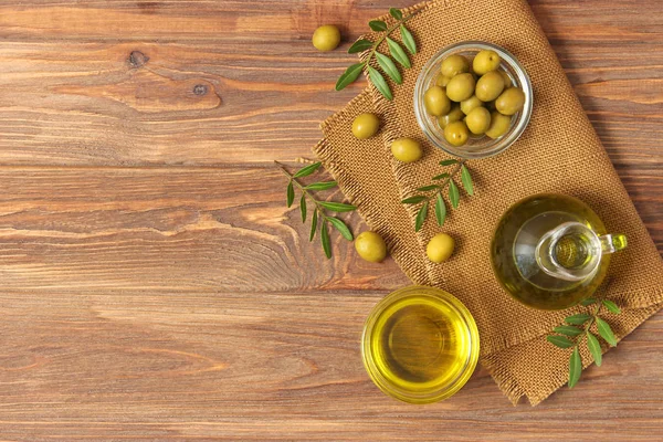 olive oil, green leaves and olives on the table.