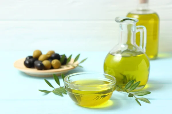 olive oil, green leaves and olives on the table.