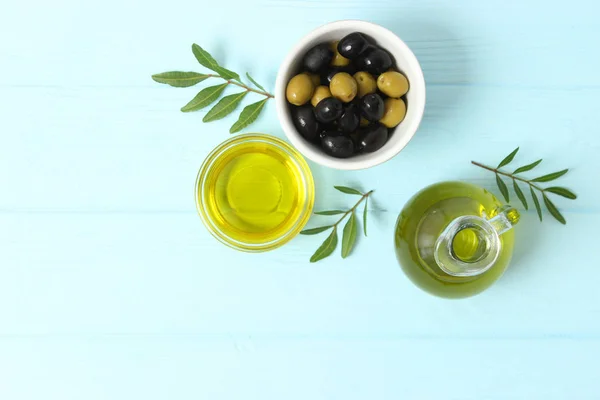 olive oil, green leaves and olives on the table.