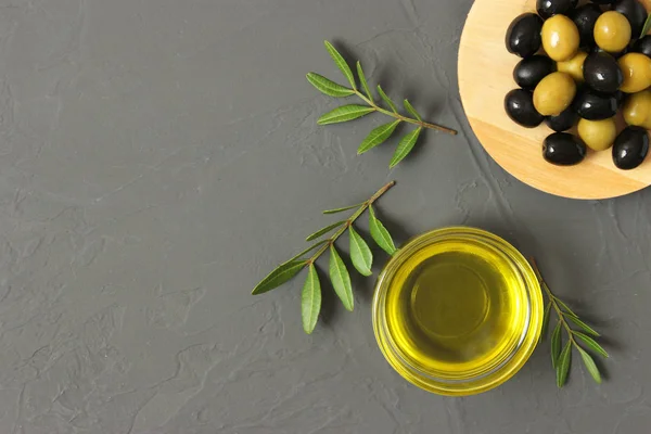 olive oil, green leaves and olives on the table.