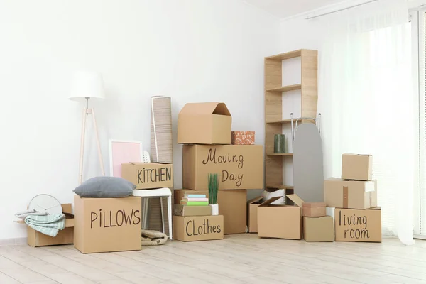 Cardboard boxes and household stuff in empty room. Moving day