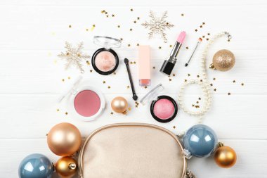 Beautiful composition with a Christmas decor and makeup cosmetics on a light background top view.