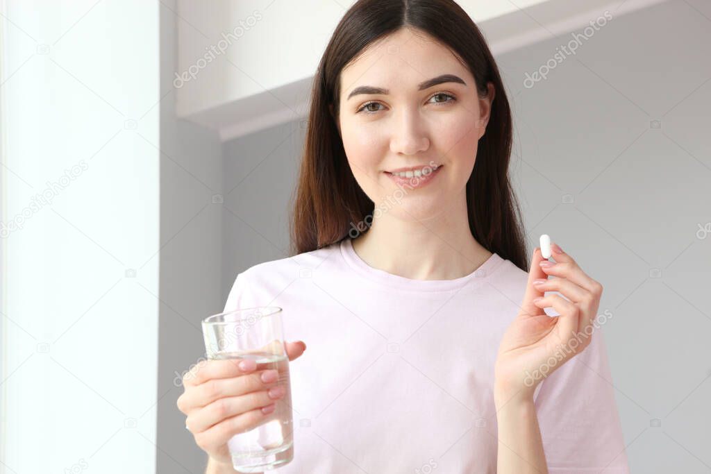 Young girl in a good mood takes pills at home