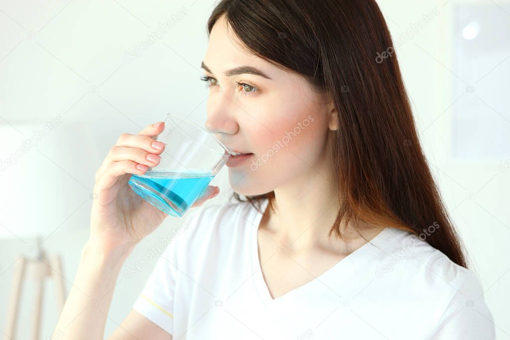 young girl uses mouthwash at home