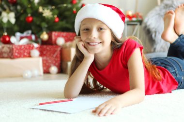 Noel arifesindeki küçük kız Noel Baba 'ya bir mektup yazıyor.