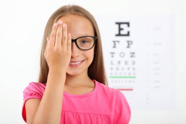Tatlı küçük kız göz doktoruyla görüşünü kontrol ediyor. Görme testi