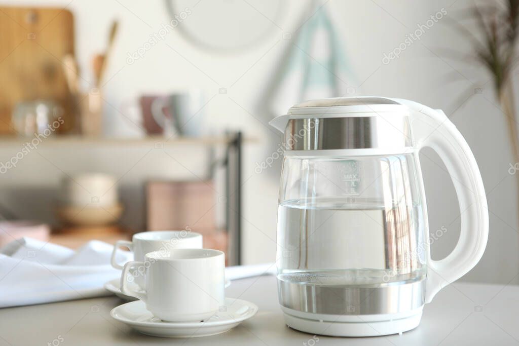 Pure water boils in an electric kettle on the table in the kitchen