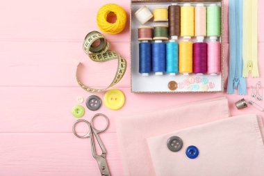 Masada farklı dikiş aksesuarları var. İplikler, iğneler, iğneler, iğneler, kumaş ve dikiş makasları kapatın.