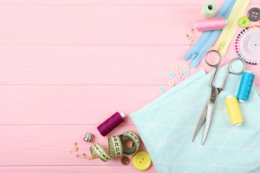 Masada farklı dikiş aksesuarları var. İplikler, iğneler, iğneler, iğneler, kumaş ve dikiş makasları kapatın.