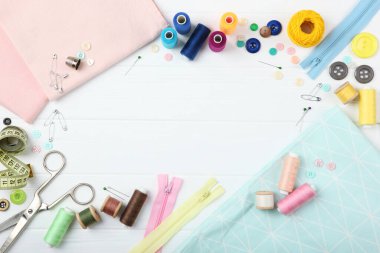 Masada farklı dikiş aksesuarları var. İplikler, iğneler, iğneler, iğneler, kumaş ve dikiş makasları kapatın.