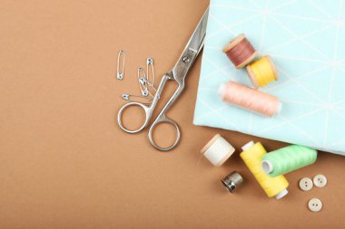 Masada farklı dikiş aksesuarları var. İplikler, iğneler, iğneler, iğneler, kumaş ve dikiş makasları kapatın.