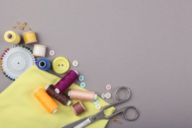 Masada farklı dikiş aksesuarları var. İplikler, iğneler, iğneler, iğneler, kumaş ve dikiş makasları kapatın.