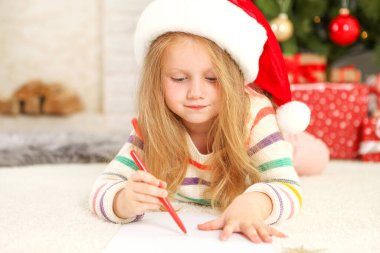 Noel arifesindeki küçük kız Noel Baba 'ya bir mektup yazıyor.