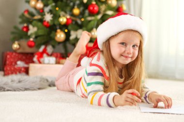Noel arifesindeki küçük kız Noel Baba 'ya bir mektup yazıyor.