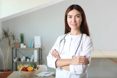 Ofisindeki genç doktor beslenme uzmanı sağlıklı beslenme kavramını gösteriyor. Ağırlık denetiminde yardım