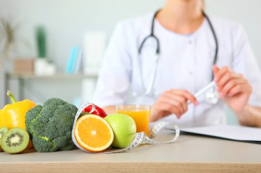 Ofisindeki genç doktor beslenme uzmanı sağlıklı beslenme kavramını gösteriyor. Ağırlık denetiminde yardım