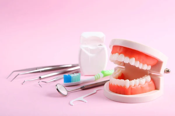 model of teeth and dental instruments and dental care products on colored background