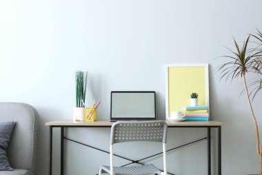Odanın içinde modern dizüstü bilgisayarı olan bir işyeri.
