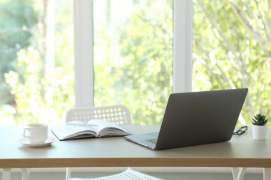 Odanın içinde modern dizüstü bilgisayarı olan bir işyeri.