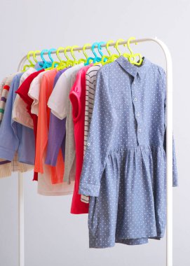 Children clothes on a rack on a light background. Children's clothing, children's stores. High quality photo. Vertical photo format
