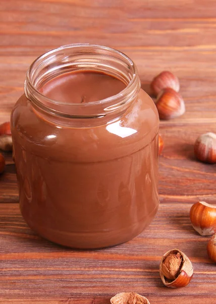 chocolate paste in a glass jar on a colored background. Chocolate butter, chocolate sauce. High quality photo. Vertical photo format