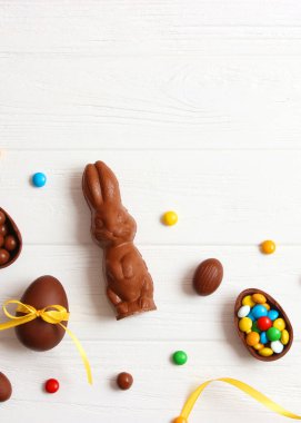 Easter composition with chocolate eggs and chocolate rabbit on wooden background, place for text. easter sweets. High quality photo. Vertical photo format