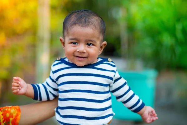Bir bebek erkek bebek bakıyor ve gülümsüyor. Giyinmiş beyaz ve lacivert çizgili elbise vardır. Bebek samimi ateş. Bebek portresi.