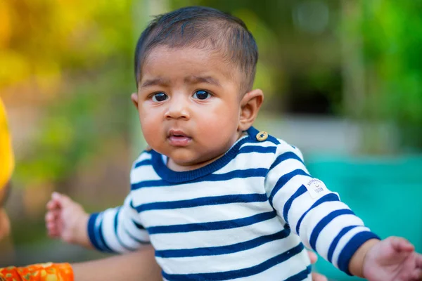 Bir bebek erkek bebek bakıyor ve gülümsüyor. Giyinmiş beyaz ve lacivert çizgili elbise vardır. Bebek samimi ateş. Bebek portresi.
