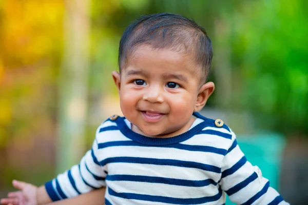 Bir bebek erkek bebek bakıyor ve gülümsüyor. Giyinmiş beyaz ve lacivert çizgili elbise vardır. Bebek samimi ateş. Bebek portresi.