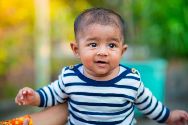 Un petit garçon qui regarde et sourit. Robe à rayures blanches et bleu marine. Tir franc pour bébé. Portrait de bébé . — Photo