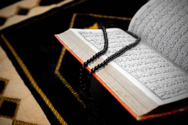 Kutsal Kur 'an' ı siyah Tasbeeh ile açın. Duaların üzerine Kur 'an-ı Kerim. Yazı tipi ve sayfalara odaklan.