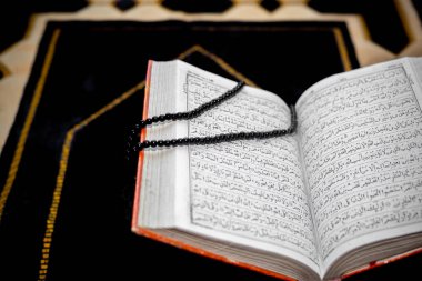 Kutsal Kur 'an' ı siyah Tasbeeh ile açın. Duaların üzerine Kur 'an-ı Kerim. Yazı tipi ve sayfalara odaklan.