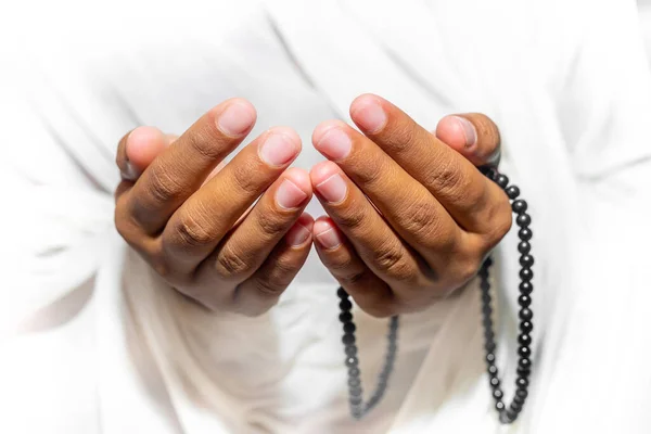 Müslüman kadınlar, beyaz arka planda, kapalı alanda Tasbeeh ile namaz kılmak için ellerini kaldırıyorlar. Ellere odaklan..