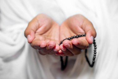 Müslüman kadınlar, beyaz arka planda, kapalı alanda Tasbeeh ile namaz kılmak için ellerini kaldırıyorlar. Ellere odaklan..