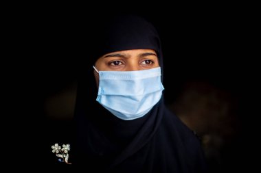 Koronavirüs koruması için cerrahi maske takan Asyalı Müslüman bir kız. Başörtülü kadın güvenlik için maske takıyor. Dikey görünümler.
