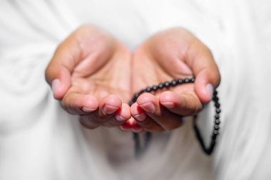 Müslüman kadınlar, beyaz arka planda, kapalı alanda Tasbeeh ile namaz kılmak için ellerini kaldırıyorlar. Ellere odaklan..