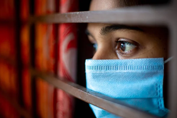 一名身穿防护外科口罩的亚洲年轻女孩 在禽流感爆发期间 她戴着防护外科口罩 看着窗外被隔离在家中 感到很无聊 总结性意见 — 图库照片