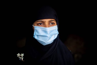 Koronavirüs koruması için cerrahi maske takan Asyalı Müslüman bir kız. Başörtülü kadın güvenlik için maske takıyor. Dikey görünümler.