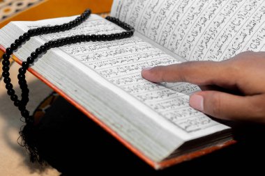 Müslüman kadın Kuran 'ı parmağıyla okuyor. Duaların üzerine Kur 'an-ı Kerim. Yakın çekim görüntüleri. İçeride. Ellere odaklan..