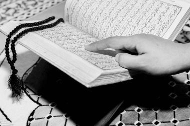 Müslüman kadın Kuran 'ı parmağıyla okuyor. Duaların üzerine Kur 'an-ı Kerim. Yakın çekim görüntüleri. İçeride. Ellere odaklan..