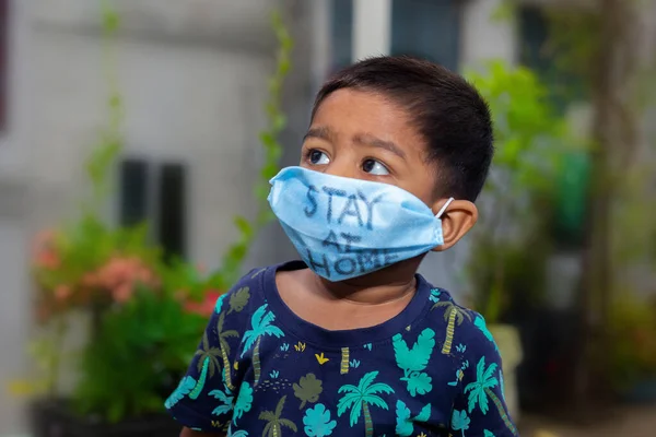 Tıbbi maske takan ve bahçede seyahat eden küçük bir çocuğun portresi. Ev karantinasındaki koronavirüs enfeksiyonundan koru..