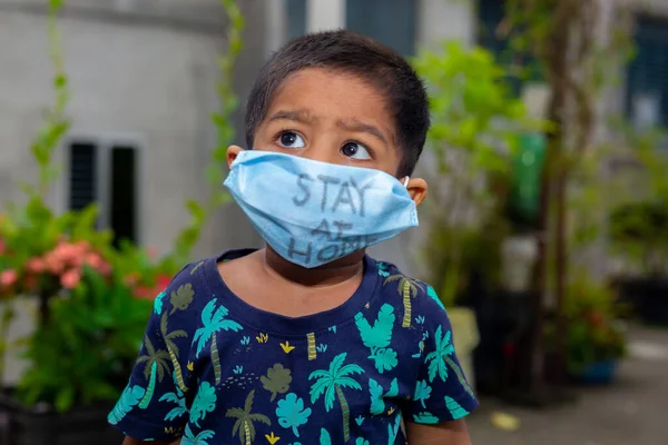 Tıbbi maske takan ve bahçede seyahat eden küçük bir çocuğun portresi. Ev karantinasındaki koronavirüs enfeksiyonundan koru..