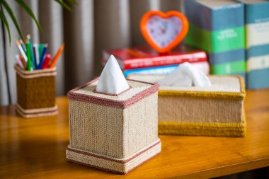 Tahta bir okuma masasının üzerinde bir mendil kutusu. Liften yapılmış bir mendil kutusu. Ananas yaprağı lifleri.