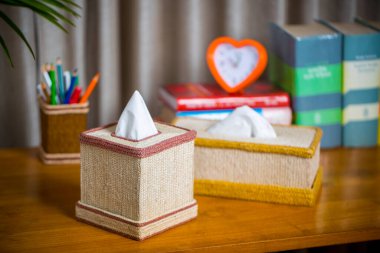 Tahta bir okuma masasının üzerinde bir mendil kutusu. Liften yapılmış bir mendil kutusu. Ananas yaprağı lifleri.